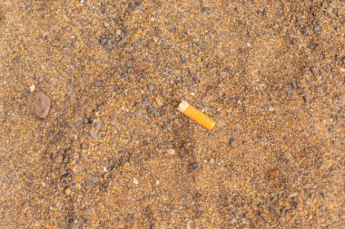 A cigarette lying on the sand on the beach