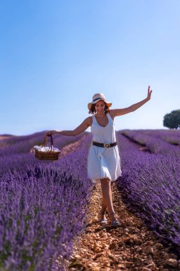 A caucasian woman in a summer lavender field with a hat picking flowers, lifestyle
