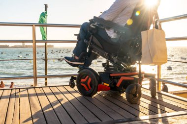 Disabled man sitting in the wheelchair looking at the sunset