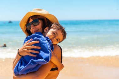 Mother hugging her son by the sea on vacation, Algarve beach, Albufeira. Portugal
