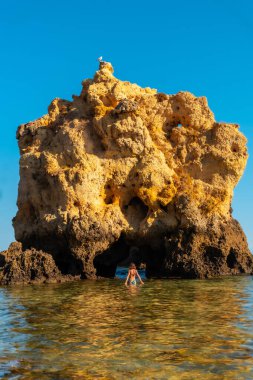 A woman in the water on a bow at Praia dos Arrifes, Algarve beach, Albufeira. Portugal