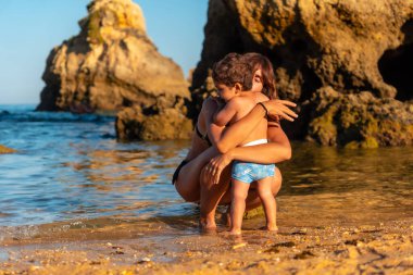 A mother hugging her son on the beach at Praia dos Arrifes, Algarve beach, Albufeira. Portugal