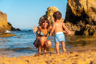 A mother hugging her son on the beach at Praia dos Arrifes, Algarve beach, Albufeira. Portugal