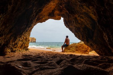 A man in the natural cave in the Algarve on the beach at Praia da Coelha, Albufeira. Portugal