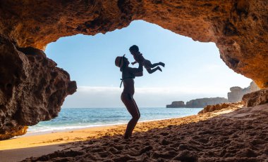 Mother with son in the cave on the beach in the Algarve, Praia da Coelha, Albufeira. Portugal