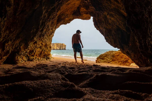 A man in the natural cave in the Algarve in summer on the beach at Praia da Coelha, Albufeira. Portugal
