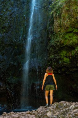 A young woman at the impressive waterfall at the Levada do Caldeirao Verde, Queimadas, Madeira
