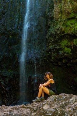 A young woman at the waterfall at the end of the waterfall trail at Levada do Caldeirao Verde, Queimadas, Madeira