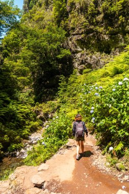 A young woman on the trail next to the waterfall at Levada do Caldeirao Verde, Queimadas, Madeira