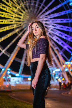 Şehirde Noel, kışın dekorasyon. Sarışın kız aydınlanmış dönme dolapta gülümsüyor.