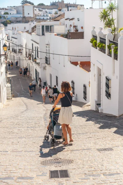 A young woman with her baby with the stroller visiting the tourist city of Vejer de la Frontera, Cadiz. Andalusia