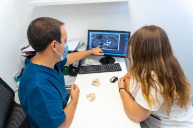 Diş hekimliği, dişçi kadın müşteriye bütçeye takılacak dişleri açıklıyor.