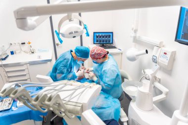 Diş hekimliği, mavi takım elbiseli dişçiler implant yapıyorlar, operasyonun yukarıdan görünüşü