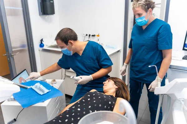 Dental clinic, dentist and assistant performing a 3d scan of the lying patient