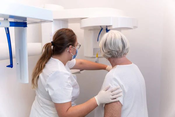 Dental clinic, dental assistant with an elderly woman in the x-ray room