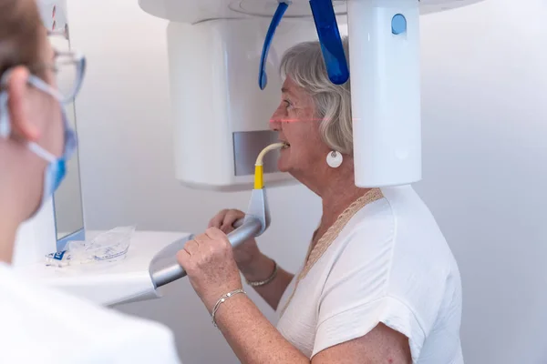 Dental clinic, dental assistant with an elderly woman in the x-ray room, explaining how they have to put the voice