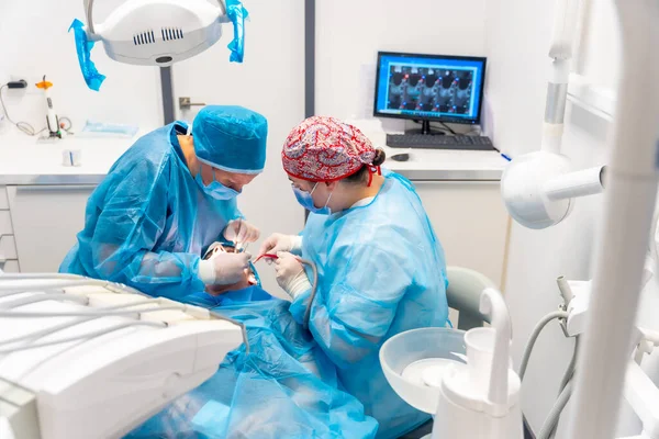 Diş kliniği, mavi elbiseli diş hekimlerinin ameliyat sonrası görüntüsü.