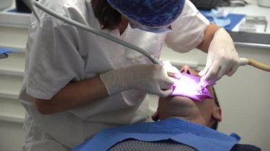 Diş sağlığı kliniği, bir hastaya endodontik ameliyat yapan bir doktor.