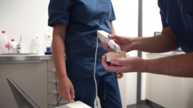 Diş sağlığı kliniğinde bir doktor, dişçi doktoruna takma dişin nasıl taranacağını anlatıyor.