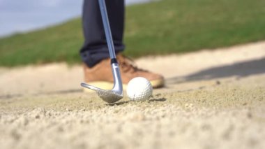 Sığınakta golf oynayan bir adamın ayakları topa sopayla vuruyor.
