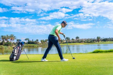 Profesyonel golf sahasında erkek golfçü. Golf sopasıyla golfçü atışı hazırlıyor.