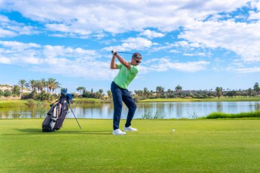 Profesyonel golf sahasında erkek golfçü. Golfçü sopayla topa vuruyor.