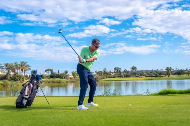 Profesyonel golf sahasında erkek golfçü. Golfçü sopayla topa vuruyor.