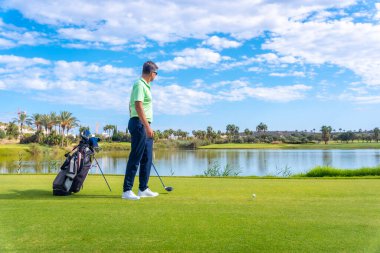 Profesyonel golf sahasında erkek golfçü. Şoförlü bir golfçü, göl kenarında.