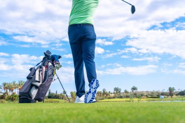 Golf kulübünde göl kenarında golf oynayan bir adam, topa vuruyor.