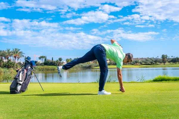 Male golf player on professional golf course. Golfer with golf driver stick preparing the shot