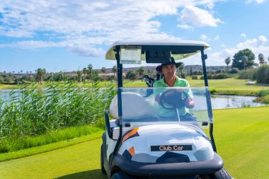 Golf oynayan adam, at arabasında golf sahasından bir sonraki sahaya doğru ilerliyor.