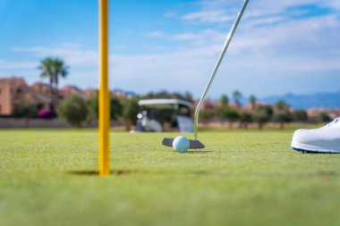 Golf oynayan bir adam, golf sopasıyla yeşile vuran bir adam.