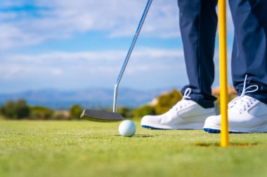Topu golf sopasıyla yeşildeki deliğe sokuyorum. Golf oynayan adam.