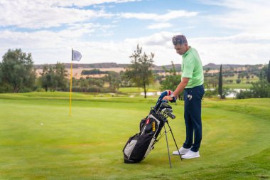 Beyazlı profesyonel golfçü golf sahasında atış için hazırlanıyor.