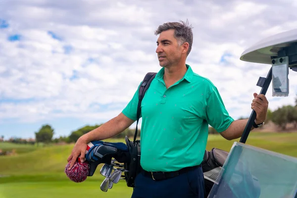 stock image Portrait of a caucasian man playing golf next to the buggy on a cloudy day