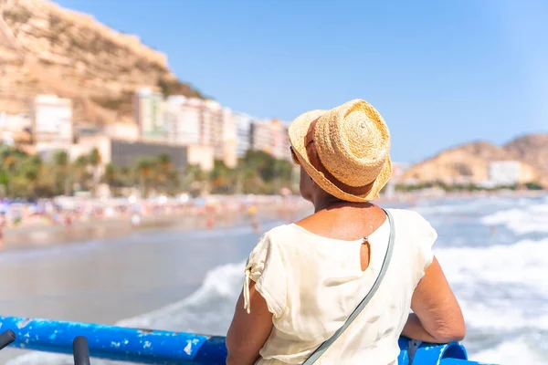 An elderly lady on the Postiguet beach in the city of Alicante, inserted trips, vacations for the elderly