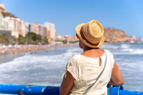 An elderly lady on the Postiguet beach in the city of Alicante, inserted trips, vacations for the elderly