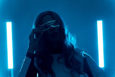 Gelecekten gelen genç bir kadının silüeti. Kameraya bakan parlak artırılmış gerçeklik gözlükleriyle.