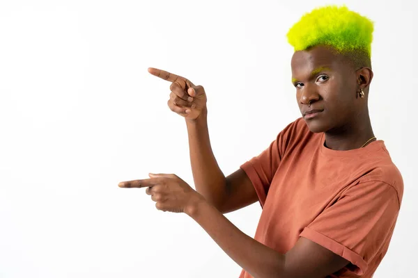 A gay black man in studio against a white background, LGTBI concept, pointing to the left