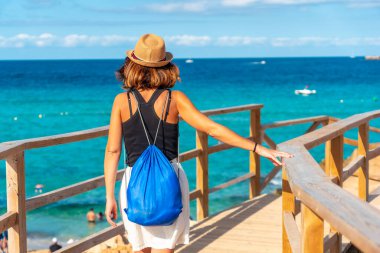 İbiza adasındaki Cala Comte plajında yürüyen bir turist. Gün batımı. Balearic