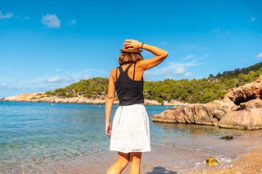 Salada y Saladeta plajında İbiza 'da tatil yapan şapkalı genç bir kadın. Balearic