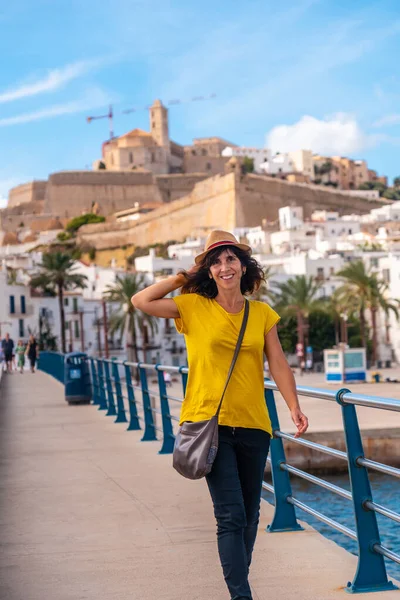 A young woman with a hat on vacation in spring in Ibiza town next to the lighthouse, Balearic Islands
