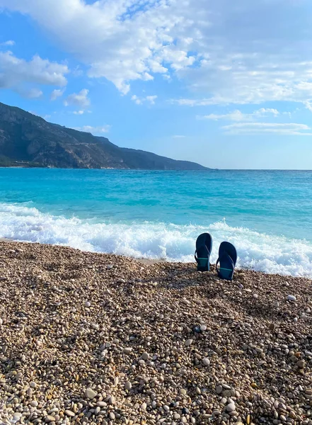 Sommerszene mit Flip-Flops, die auf einem kleinen Stein vor dem schönen türkisfarbenen Meer stehen. Weiche selektive Fokussierung. Sommer oder Reisekonzept — Stockfoto