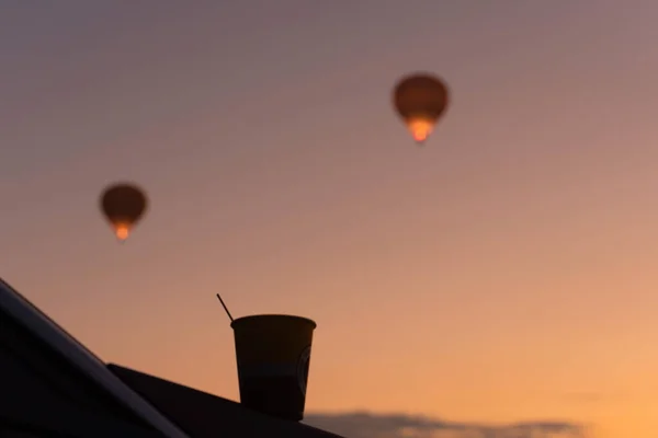 Une tasse de café du matin contre une vue magique floue avec ballon à air chaud dans le ciel pendant le lever du soleil. Concept de moment inspirant. La meilleure mendicité de la journée. Petit déjeuner extérieur — Photo