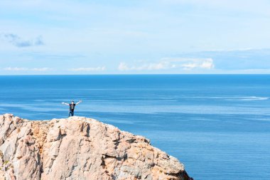 Dünyanın sonundaki bir kayanın üzerinde duran adam. Yürüyüş ya da seyahat konsepti. Açık havayı keşfet. Doğanın güzelliği