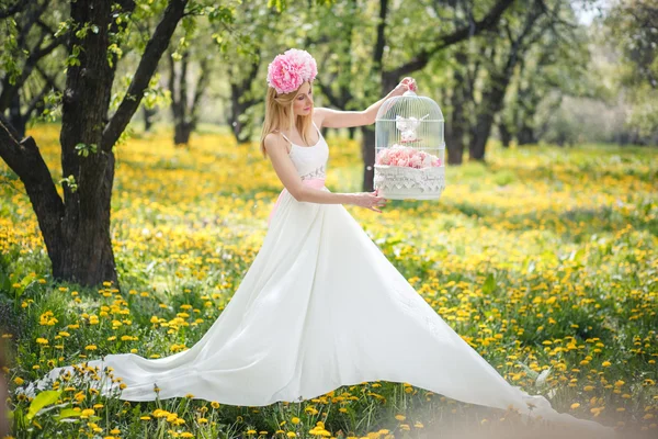 Jovem menina bonita está posando com flores — Fotografia de Stock