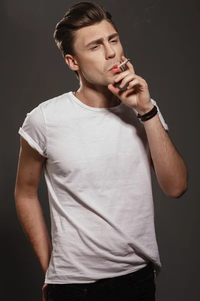 英俊的年轻男子吸烟香烟 — 图库照片