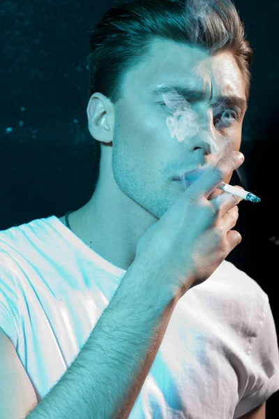 Красивый молодой человек курит сигарету — стоковое фото