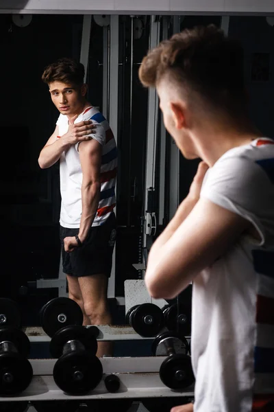 Atleta mira sus músculos en el gimnasio — Foto de Stock