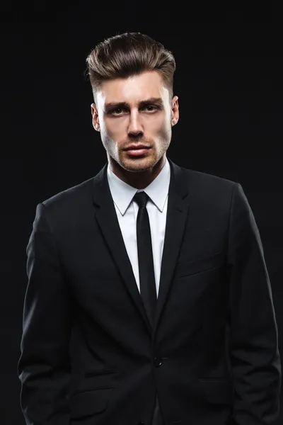 Handsome young man in suit on dark background — Stock Photo, Image